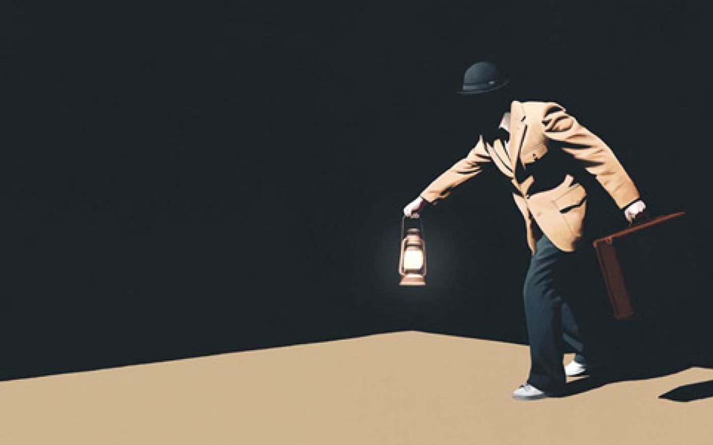 A person in a suit and hat holding a lantern and briefcase while walking through a dark setting.